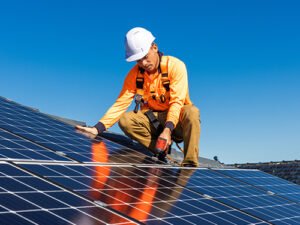 Roofer installing solar panels on a sunny day for sustainable energy solutions.