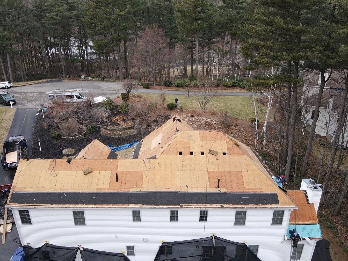 An aerial view of a white house with white windows undergoing a roof replacement.