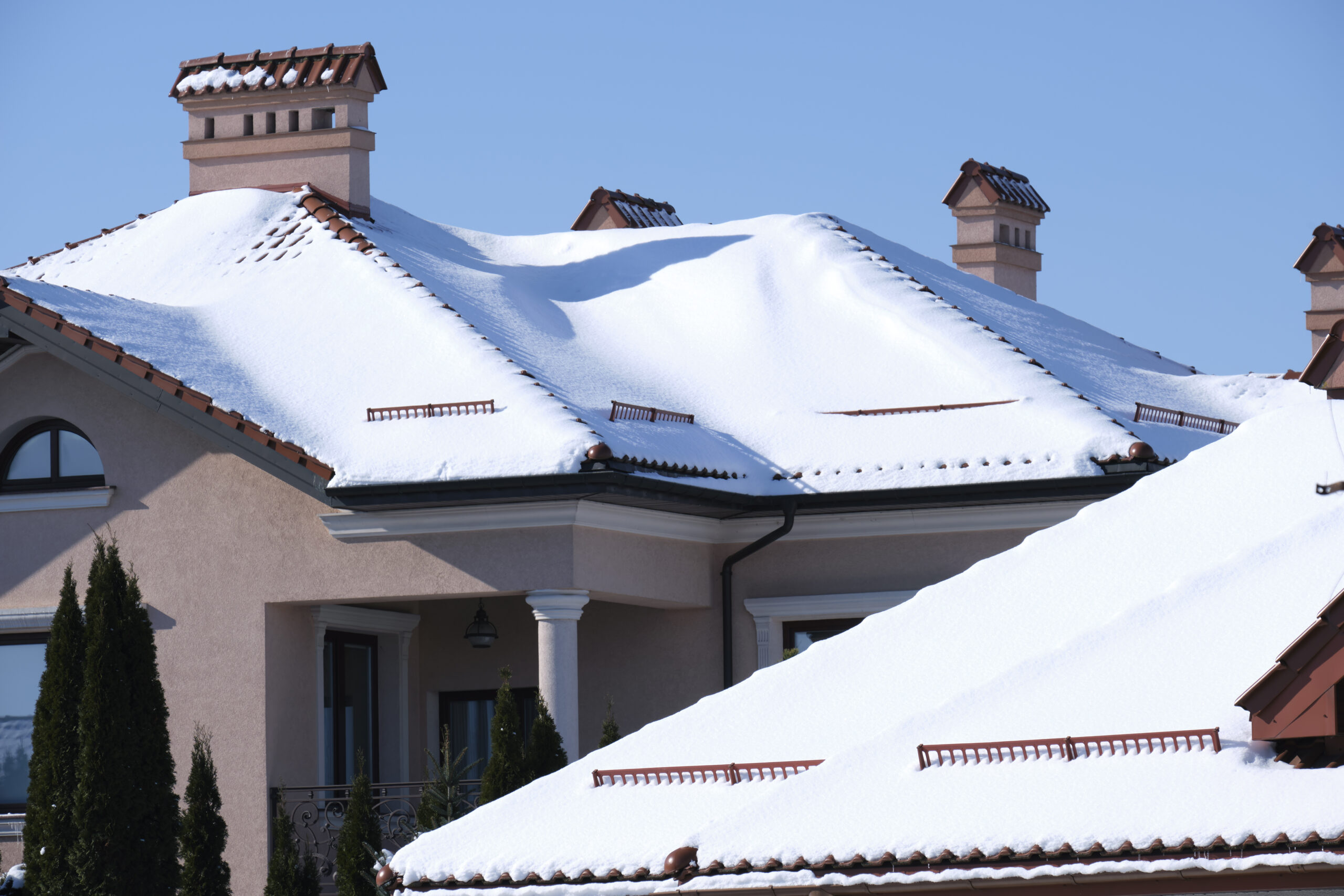 A gray house with a blanket of snow on the roof.