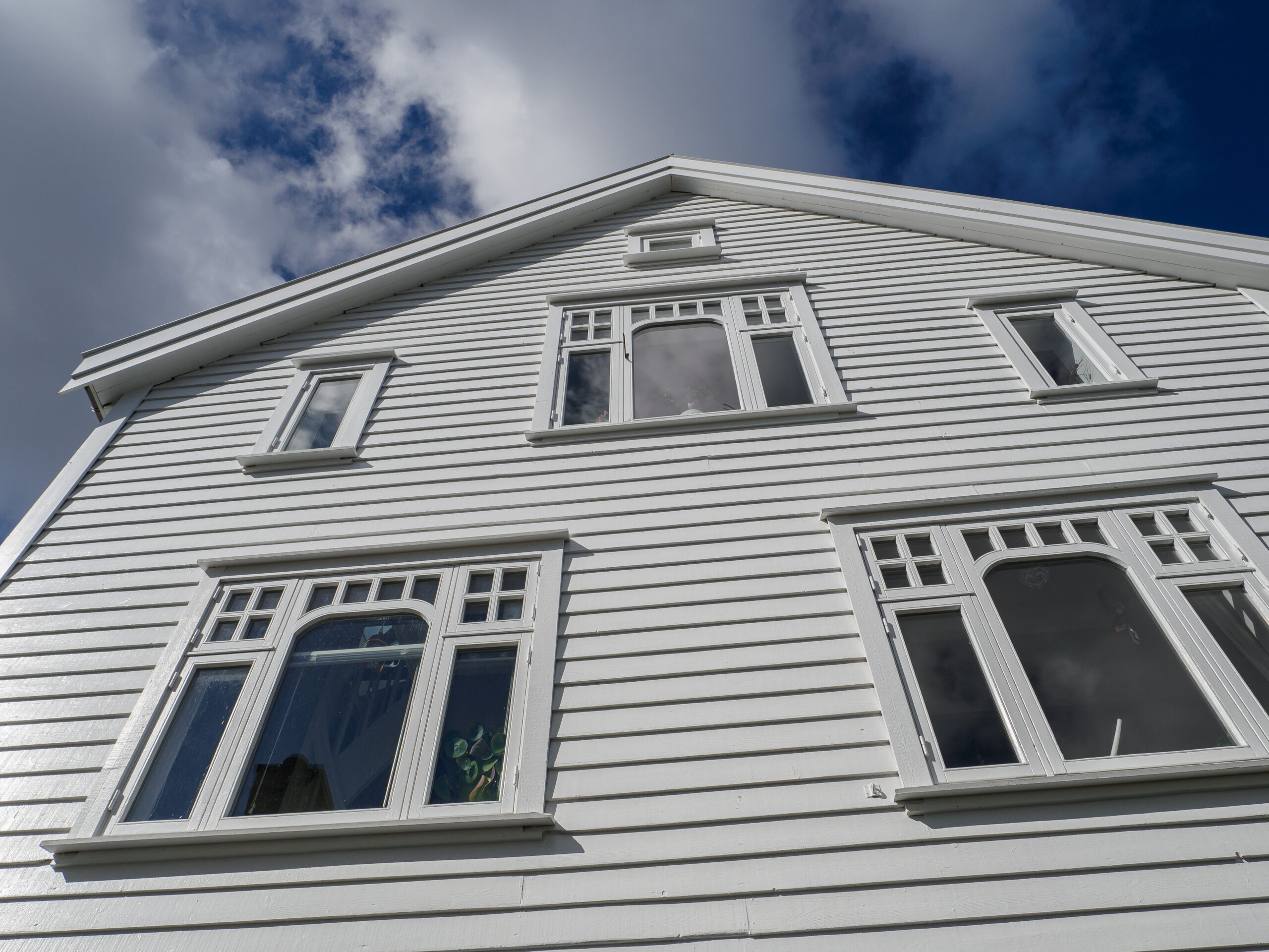 An upward look at a white house with white windows.