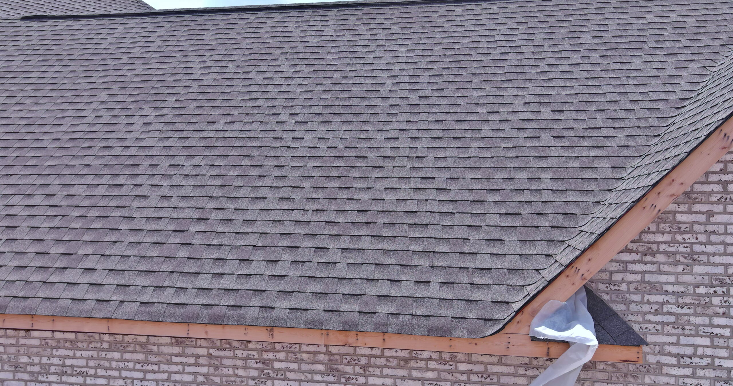 A close-up view of an asphalt shingle roof on a brick house.