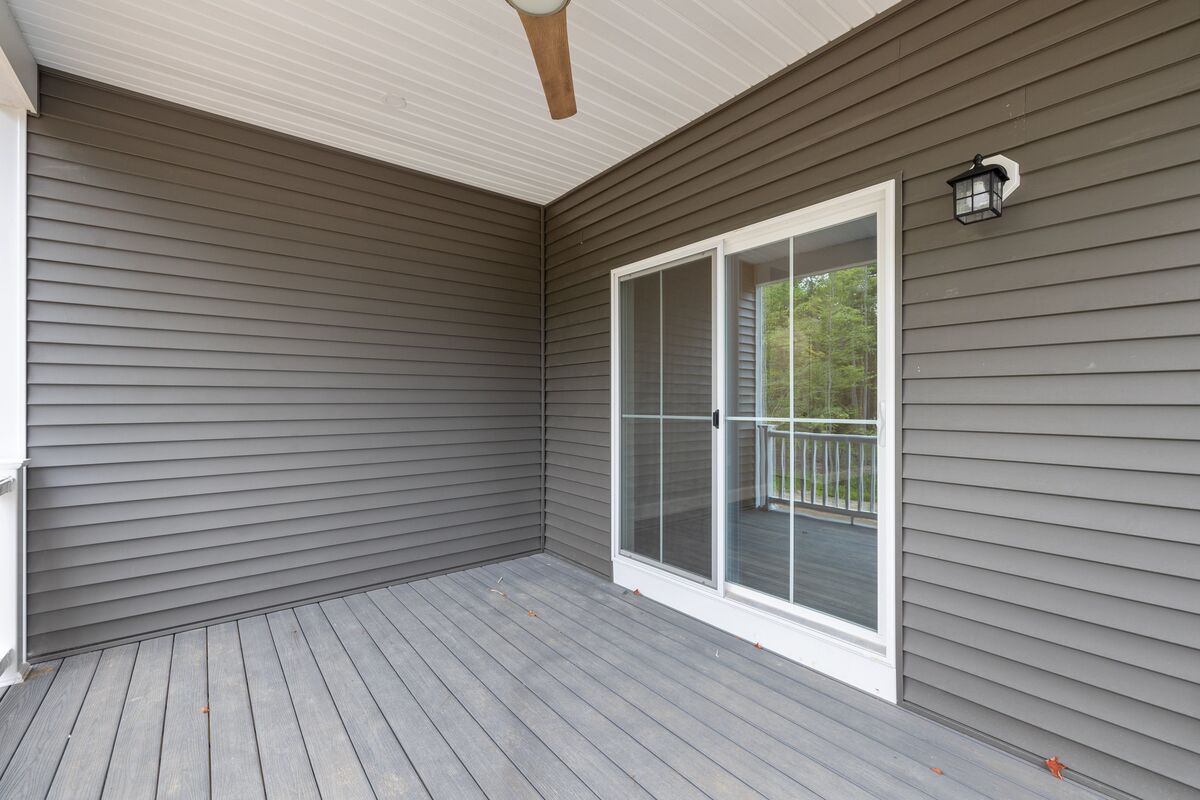A close-up view of the back porch of a brown house with a white sliding glass door.
