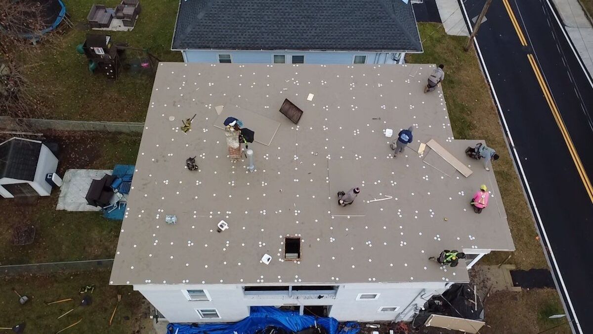 A close-up view of an asphalt shingle roof with white fascia on a white house.