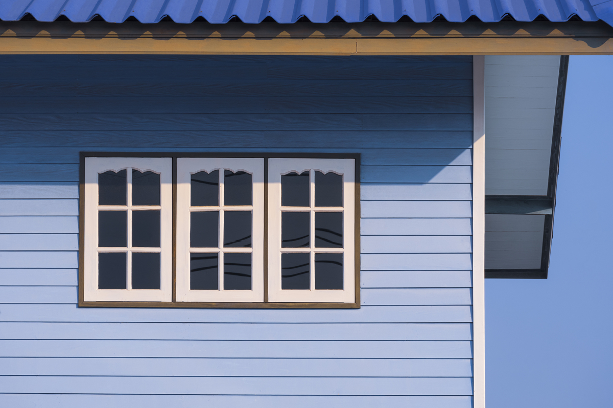 A close-up view of a blue house with white windows.