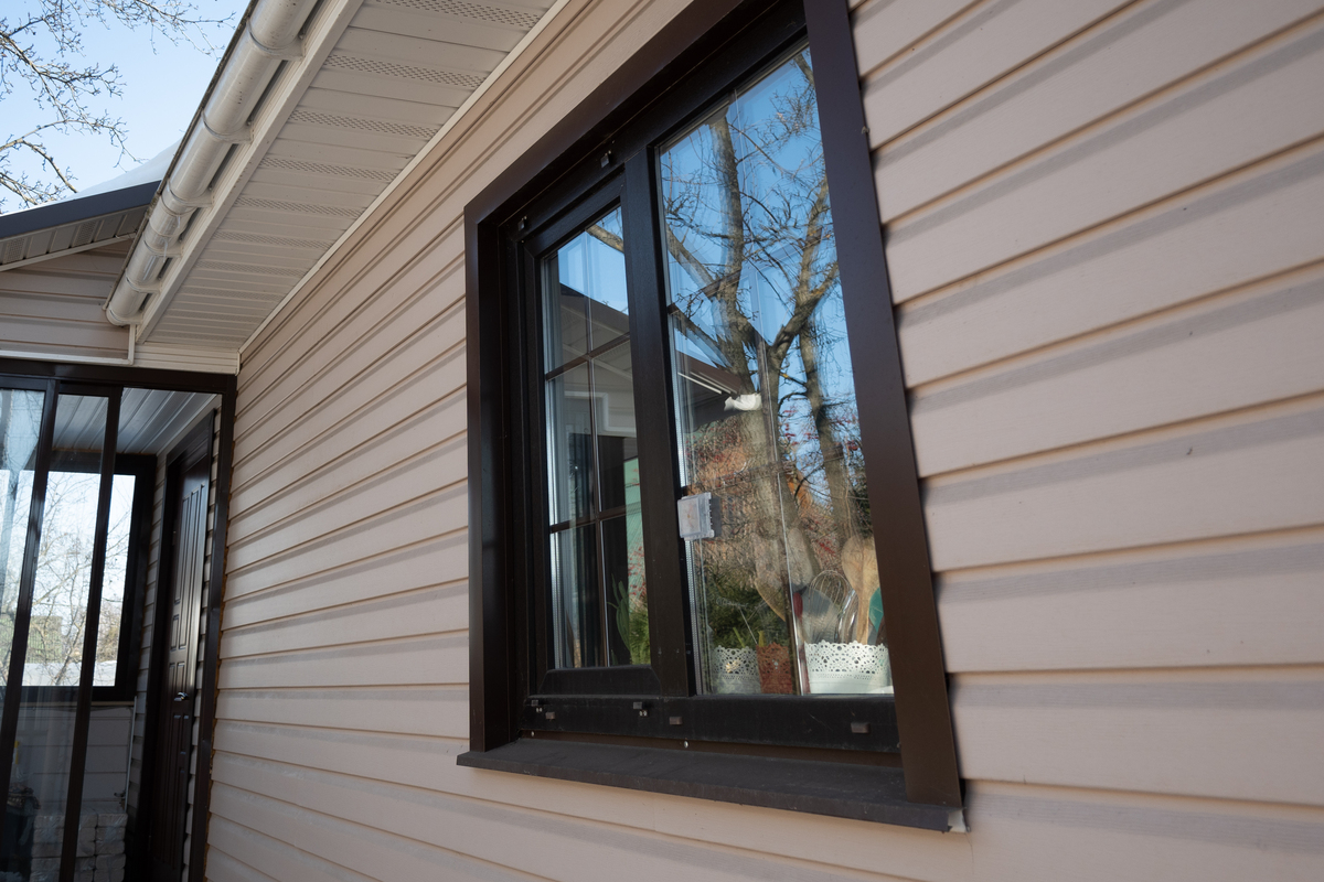 A close-up view of a tan house with brown windows.