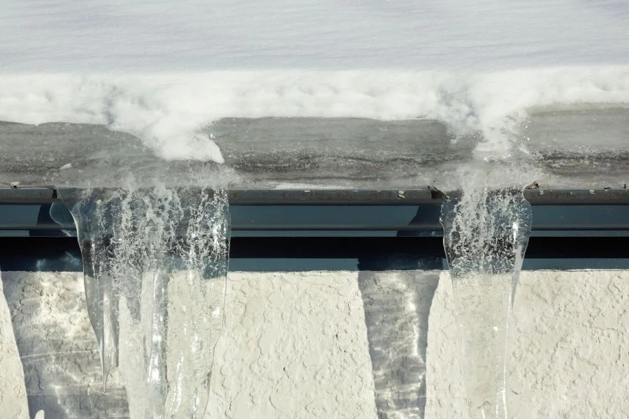 Ice dam and icicles forming along a gutter line