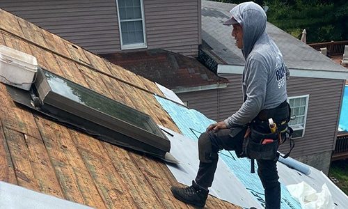 skylight11426081411 A roofer installs shingles on a residential home roof under daylight conditions.